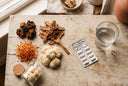 Assortiment de champignons adaptogènes séchés (chaga, reishi, cordyceps, lion's mane) à côté d'une plaquette de médicaments et d'un verre d'eau